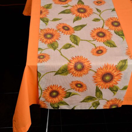 детайл от маса подредена с оранжева покривка и рънър в десен на оранжеви цветя