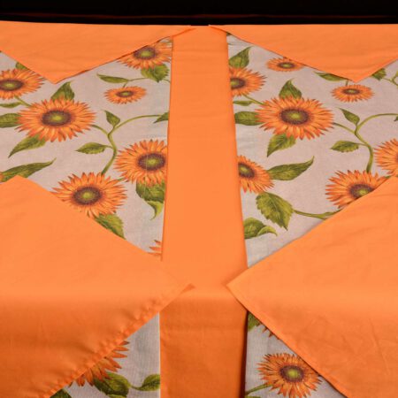 Маса постлана с оранжева покривка, оранжеви платнени кърпи и рънър на слънчогледи