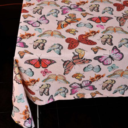 Маса аранжирана с голяма, розова покривка с пъстри пеперуди