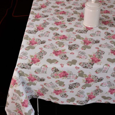 Маса застлана с покривка на сърца и аранжирана с бяла свещ