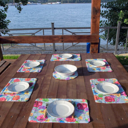 Маса край река, аранжирана с подложки за хранене и чинии