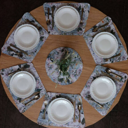 Кръгла маса аранжирана с подложки за хранене в светлосиньо, чинии, прибори и декорация