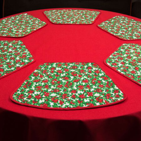 кръгла маса с червена покривка и подложки за хранене с коледни мотиви